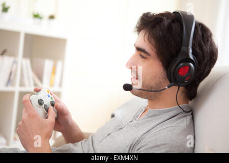 Vue d'un jeune homme séduisant à jouer à des jeux vidéo dans un canapé Banque D'Images