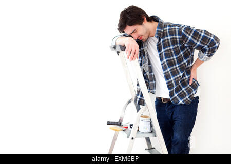 Vue d'un jeune homme souffrant tout en travaillant sur un escabeau Banque D'Images