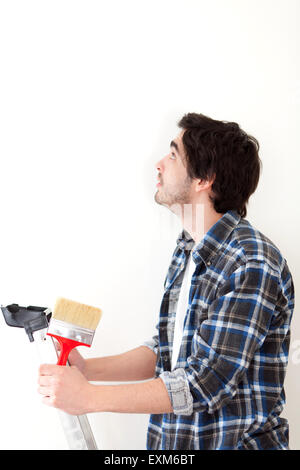 Beau jeune homme peindre un mur dans son nouvel appartement Banque D'Images