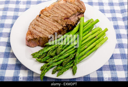 Strip steak grillé sur une plaque blanche avec les asperges Banque D'Images
