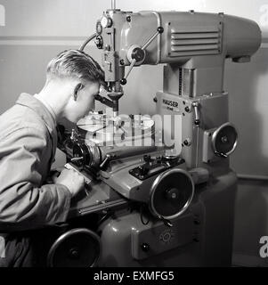 années 1950, tableau historique montrant un jeune apprenti homme utilisant une machine-outil métallique de précision à entraînement électrique. Une machine-outil est un outil électrique ou manuel pour l'usinage du métal par coupe, meulage ou façonnage. Banque D'Images