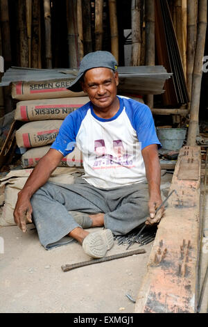 Construction Worker smiling en restant assis dans son travail sur un chantier à malang indonésie Banque D'Images