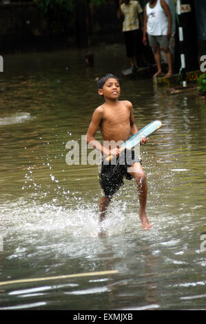 Inondations de pluie de mousson, garçon jouant au cricket inondé rue, Bombay, Mumbai, Maharashtra, Inde, Asie Banque D'Images