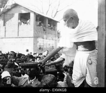 Mahatma Gandhi la collecte de dons pour financer Harijan avec un panier à la main dans une gare sur sa façon d'Assam en Inde Janvier 1946 Banque D'Images