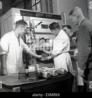 Historique Années 1950 Photo d'étudiants ou apprentis étant montré comment utiliser un grand four industriel pour faire des baguettes de pain. Banque D'Images