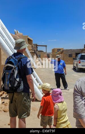 Guide touristique à côté de l'échelle en bois menant à l'entrée d'une kiva. Acoma Pueblo. Cibola County, Nouveau Mexique, USA Banque D'Images