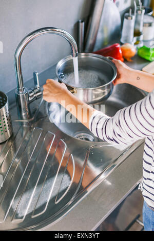 Femme versant de l'eau dans une marmite Banque D'Images