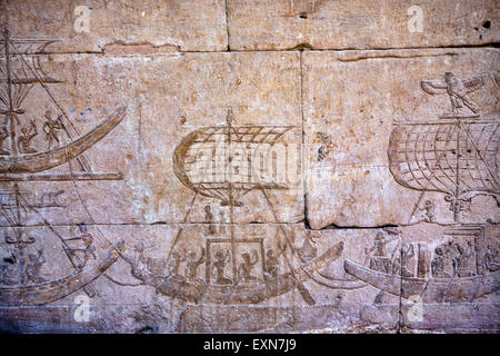 Sculptures anciennes de bateaux remplis de gens sur les murs trouvés au temple de Idfu en Égypte. Banque D'Images