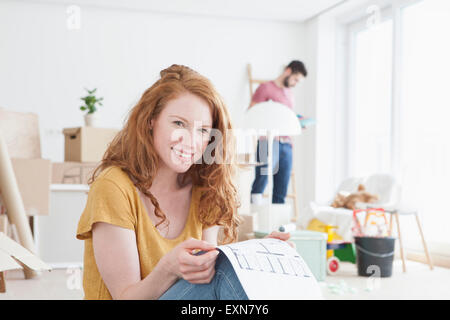 Jeune couple télévision, woman holding plan au sol Banque D'Images