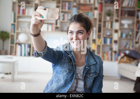 Jeune femme tenant un smartphone avec selfies at home Banque D'Images