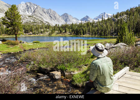 Randonneur au repos admire vue dans la vallée des lacs à Rock Creek Canyon dans l'Est de la Sierra en Californie du Nord Banque D'Images