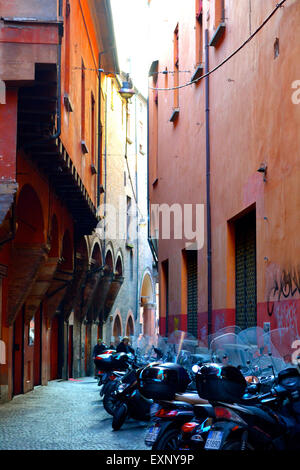 Motos garées sur une rue étroite rouge typique de Bologne, Italie Banque D'Images