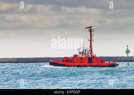 Remorqueur rouge navigue dans le port dans un jour nuageux en attente d'un navire Banque D'Images