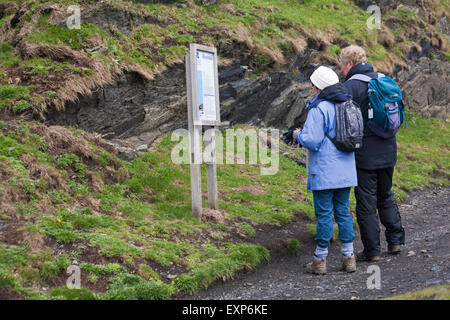 Couple lisant le signe National Trust à Abereiddy avec des informations sur le Blue Lagoon, Pembrokeshire Coast National Park, pays de Galles UK en mai - Abereiddi Banque D'Images