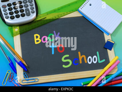 Retour à l'école message sur tableau noir avec des fournitures scolaires entourant Banque D'Images