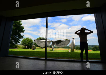 Un Yorkshire Sculpture Park visiteur regarde à travers une fenêtre pour voir le travail de l'intérieur trouve par le sculpteur Sir Anthony Caro. Travailler par le sculpteur peut être vu dans une nouvelle grande exposition 'Caro', dans le Yorkshire, qui ouvre au public le 18 juillet 2015. Photo : Scott Bairstow/Alamy Banque D'Images