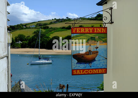 Salcombe, Devon, UK. Le Ferry Inn Pub signe à Salcombe avec rivière et voile en arrière-plan. Banque D'Images