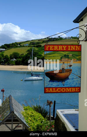 Salcombe, Devon, UK. Le Ferry Inn Pub signe à Salcombe avec rivière et voile en arrière-plan. Banque D'Images