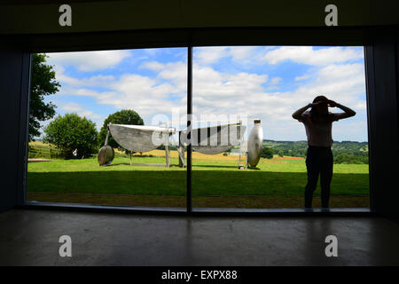 Un Yorkshire Sculpture Park visiteur regarde à travers une fenêtre pour voir le travail de l'intérieur trouve par le sculpteur Sir Anthony Caro. Travailler par le sculpteur peut être vu dans une nouvelle grande exposition 'Caro', dans le Yorkshire, qui ouvre au public le 18 juillet 2015. Photo : Scott Bairstow/Alamy Banque D'Images