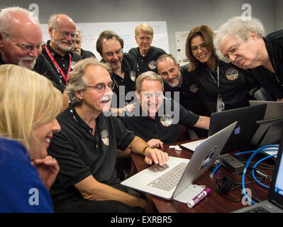 Les membres de l'équipe de Nouveaux Horizons se rassemblent autour d'un ordinateur portable et sourire lors de l'examen des nouvelles images traitées à partir de la sonde New Horizons à la Johns Hopkins University Applied Physics Laboratory, 15 juillet 2015 à Laurel, Maryland. Banque D'Images