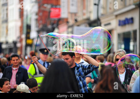 Un homme crée des bulles de savon géantes pour amuser les enfants dans le centre de Dublin en Irlande. Banque D'Images