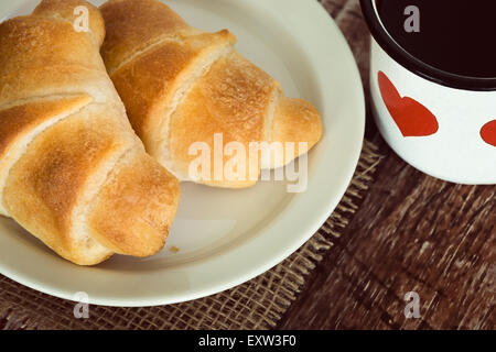 Petit-déjeuner croissants et une tasse de café contre fond rustique vintage Banque D'Images