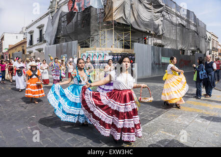 Jolies femmes autochtones mexicains portant des costumes traditionnels aux couleurs vives prendre part au défilé dans le centre historique de Oaxaca Banque D'Images