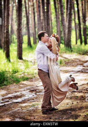 Couple aimant s'amuser dans la forêt, les baisers et qui tournoient autour d'eux-mêmes, heureux mariés appréciant jour de mariage Banque D'Images