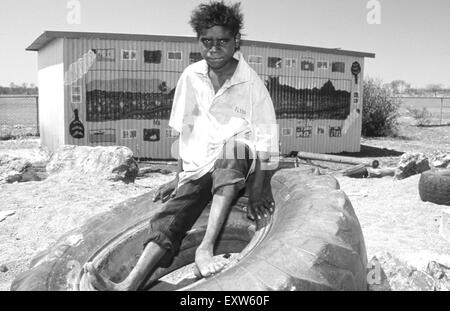 Teenage boy sitting autochtones sur le pneu, Yuelamu (Mount Allan) dans le Territoire du Nord, Australie Banque D'Images
