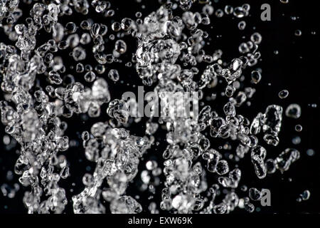 Léviter des gouttes d'eau sur fond sombre, la pluie ou le jet d'eau Banque D'Images