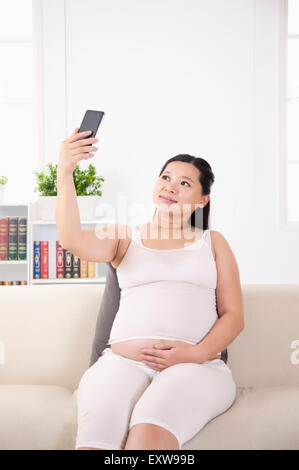 Pregnant woman holding mobile phone et prise de la photo, Banque D'Images