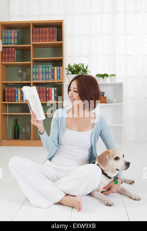 Jeune femme assise avec chien et lire un livre avec le sourire, Banque D'Images