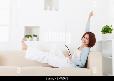 Jeune femme assise sur un canapé et souriant à la caméra, Banque D'Images