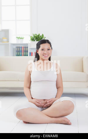 Pregnant woman sitting and smiling at the camera, Banque D'Images