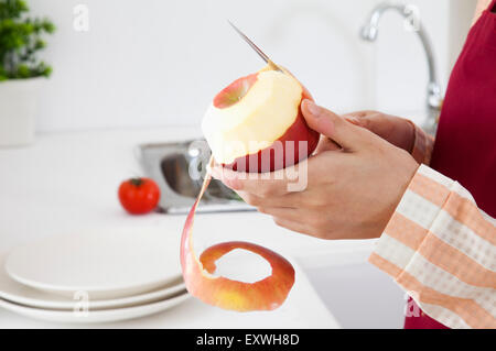 Young woman peeling une pomme dans la cuisine, Banque D'Images