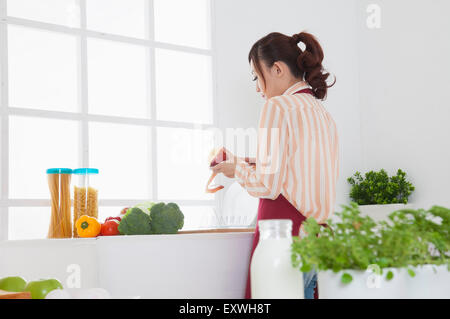 Young woman peeling une pomme dans la cuisine, Banque D'Images