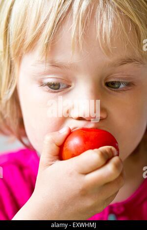 Girl eating a tomato Banque D'Images