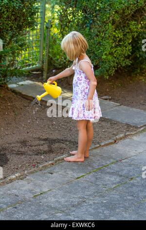 Girl watering plants in garden Banque D'Images