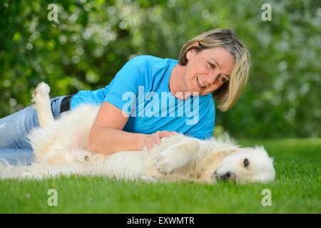 Femme mature avec un golden retriever dans jardin Banque D'Images