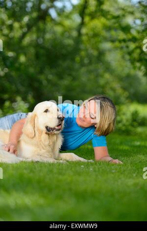 Femme mature avec un golden retriever dans jardin Banque D'Images