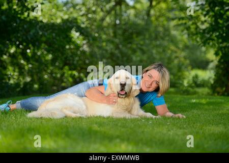 Femme mature avec un golden retriever dans jardin Banque D'Images