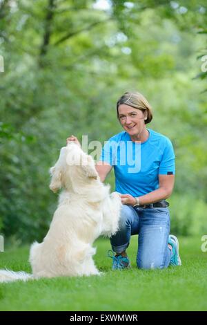 Femme mature avec un golden retriever dans jardin Banque D'Images