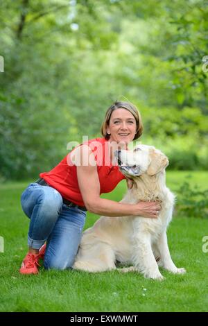 Femme mature avec un golden retriever dans jardin Banque D'Images