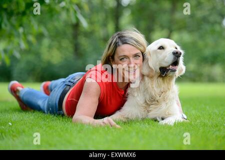 Femme mature avec un golden retriever dans jardin Banque D'Images