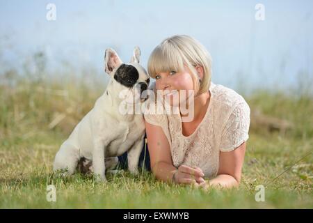 Femme couchée sur prairie avec un sept mois Bouledogue Français Banque D'Images