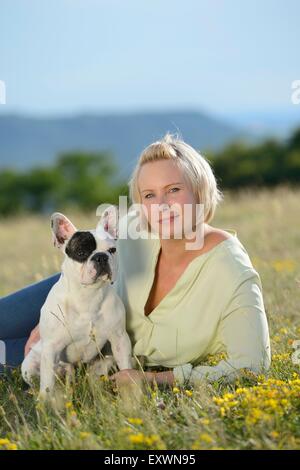 Femme couchée sur prairie avec un sept mois Bouledogue Français Banque D'Images