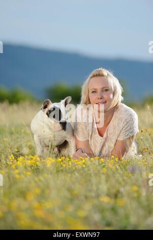 Femme couchée sur prairie avec un sept mois Bouledogue Français Banque D'Images