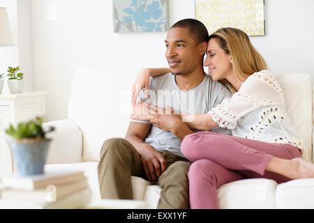 Young couple embracing in living room Banque D'Images