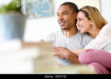 Young couple embracing in living room Banque D'Images