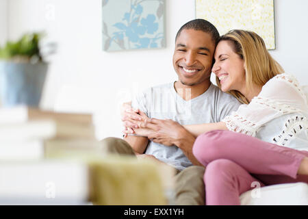 Young couple embracing in living room Banque D'Images